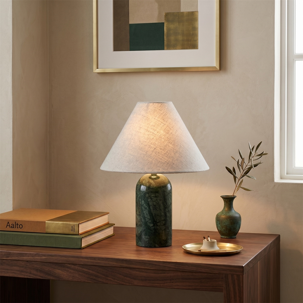 Green marble base and a pale linen shade on this Clérachic table lamp, with a brass dish and an olive sprig on a walnut desk.