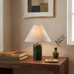 Green marble base and a pale linen shade on this Clérachic table lamp, with a brass dish and an olive sprig on a walnut desk.