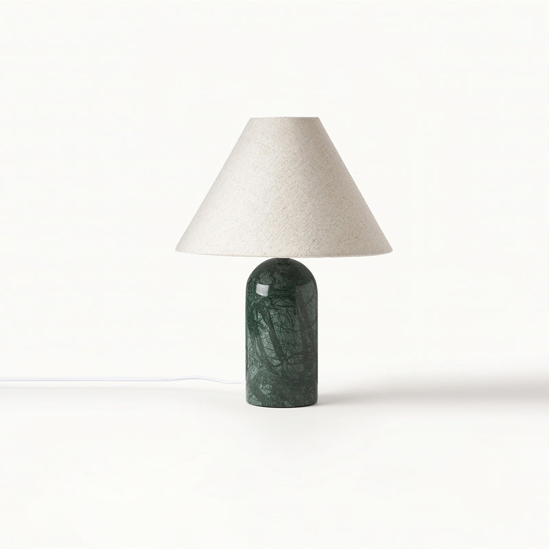 Smaller view of this Clérachic table lamp in green marble with a pale linen shade, its white cord trailing on a white backdrop.