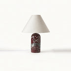 Burgundy marble base with white veining under a natural linen shade, this Clérachic table lamp shown on a white backdrop.