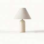 Beige marble table lamp from Clérachic with a natural linen cone shade, photographed on a plain white backdrop.