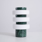 The unlit Clérachic table lamp in the green and white finish on a pale grey backdrop, white glass discs on veined green marble.