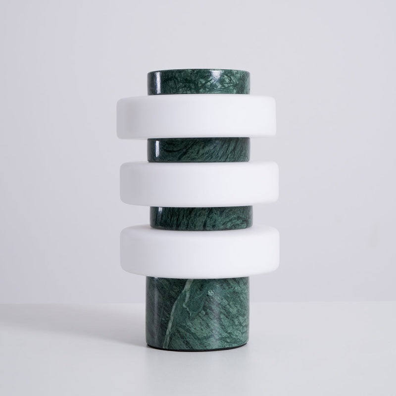 The unlit Clérachic table lamp in the green and white finish on a pale grey backdrop, white glass discs on veined green marble.