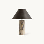 This Clérachic table lamp on a plain white backdrop, with a tapered black fabric shade above a cylindrical veined marble base.