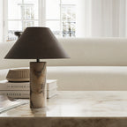 Clérachic marble table lamp on a polished stone console in front of a cream sofa and a stack of books.