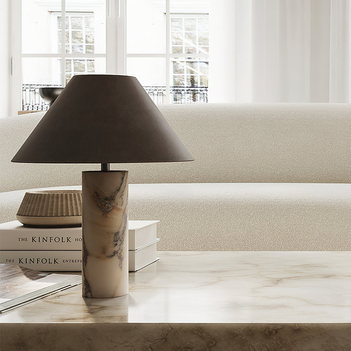 Clérachic marble table lamp on a polished stone console in front of a cream sofa and a stack of books.