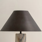 Close view of the tapered black shade and the veined marble top of the base on this Clérachic table lamp.