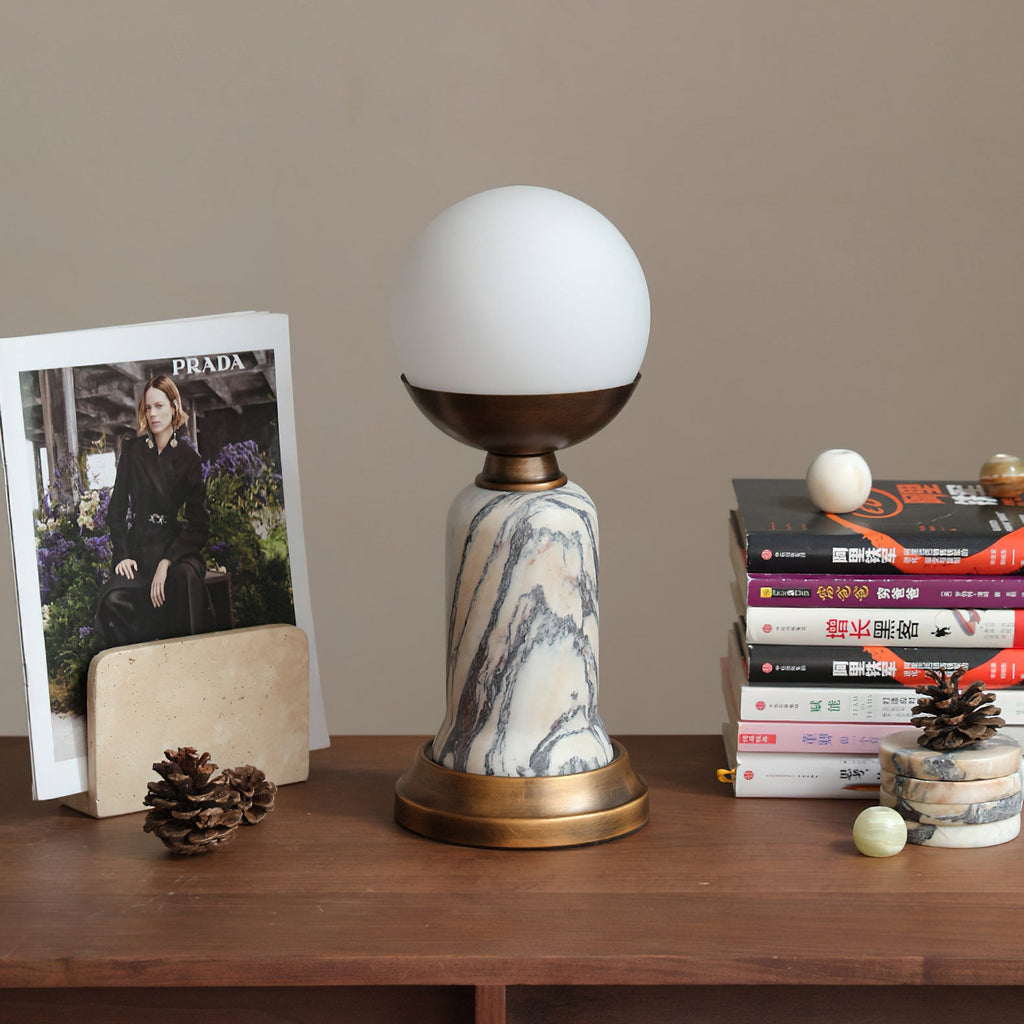 Side view of an unlit Clérachic table lamp on a wooden shelf, with a magazine, a stack of books and two small marble spheres.