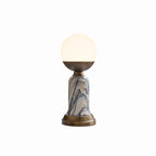A Clérachic table lamp with a white globe, bronze cup, grey-veined marble stem and bronze base, on a pale studio backdrop.