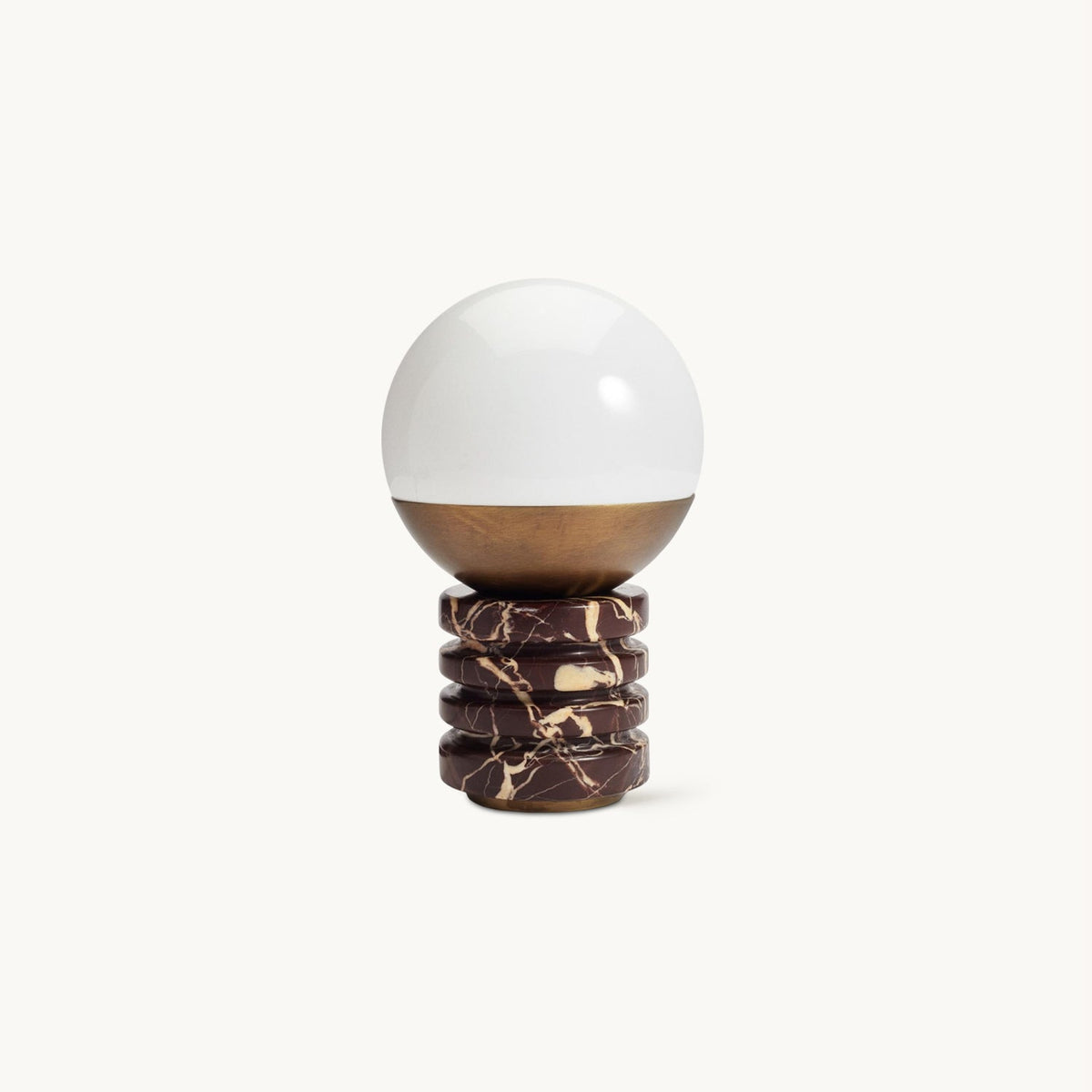 This Clérachic table lamp on a plain white backdrop, a white glass globe above a bronze cap and a ribbed red-and-cream marble base.