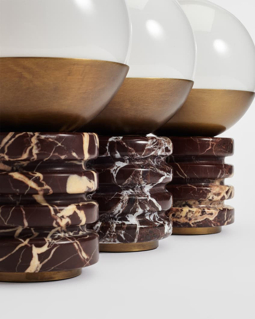 Three bases of this Clérachic lamp lined up close together, each ribbed marble ring showing its own pattern of cream and red veining.