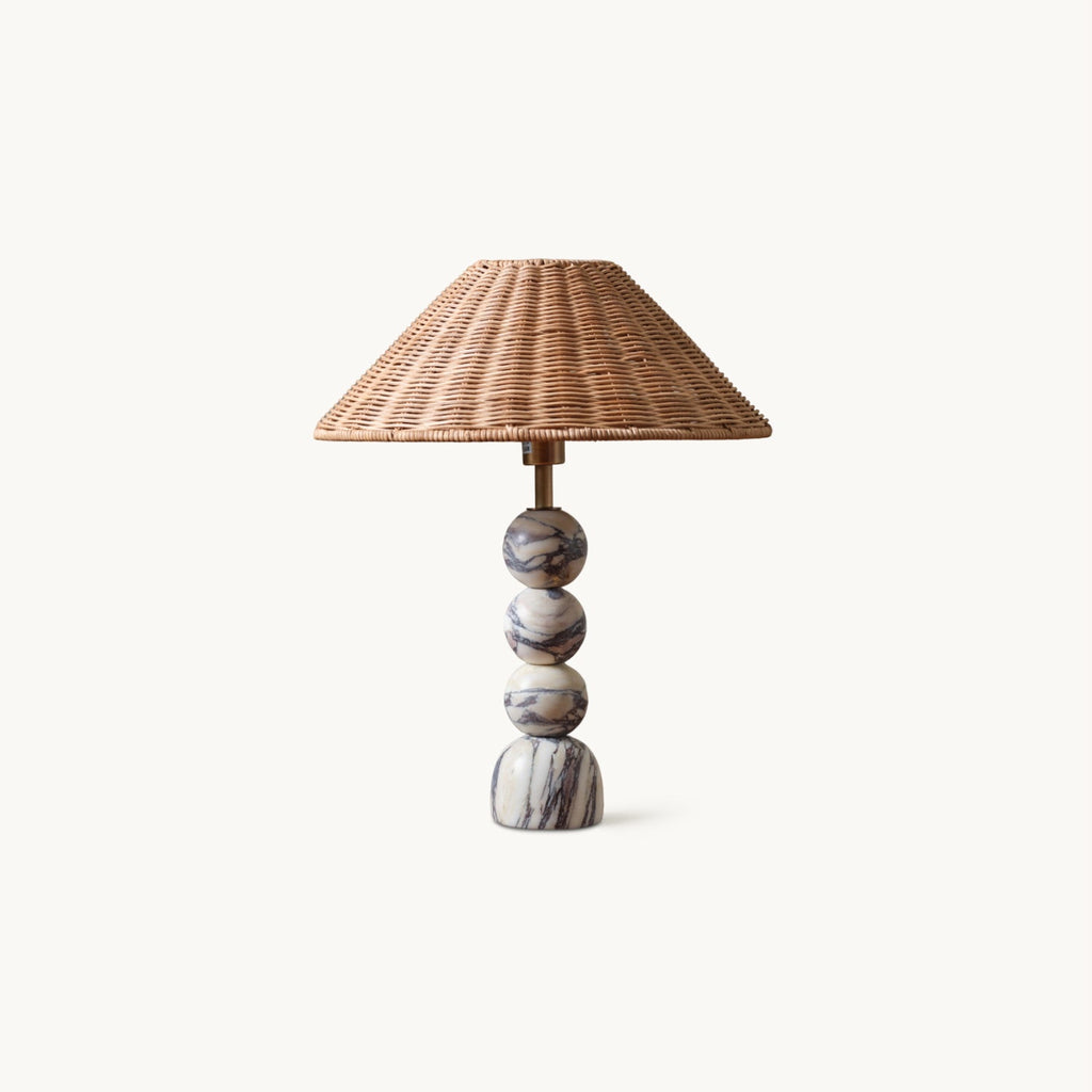 This Clérachic table lamp on a plain white backdrop, with a stacked marble ball base and a wide natural rattan shade.