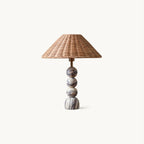 This Clérachic table lamp on a plain white backdrop, with a stacked marble ball base and a wide natural rattan shade.