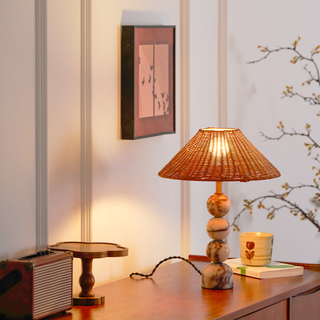 Lit Clérachic lamp with a warm rattan glow on a teak sideboard, with a retro radio, a small stand and a patterned cup.