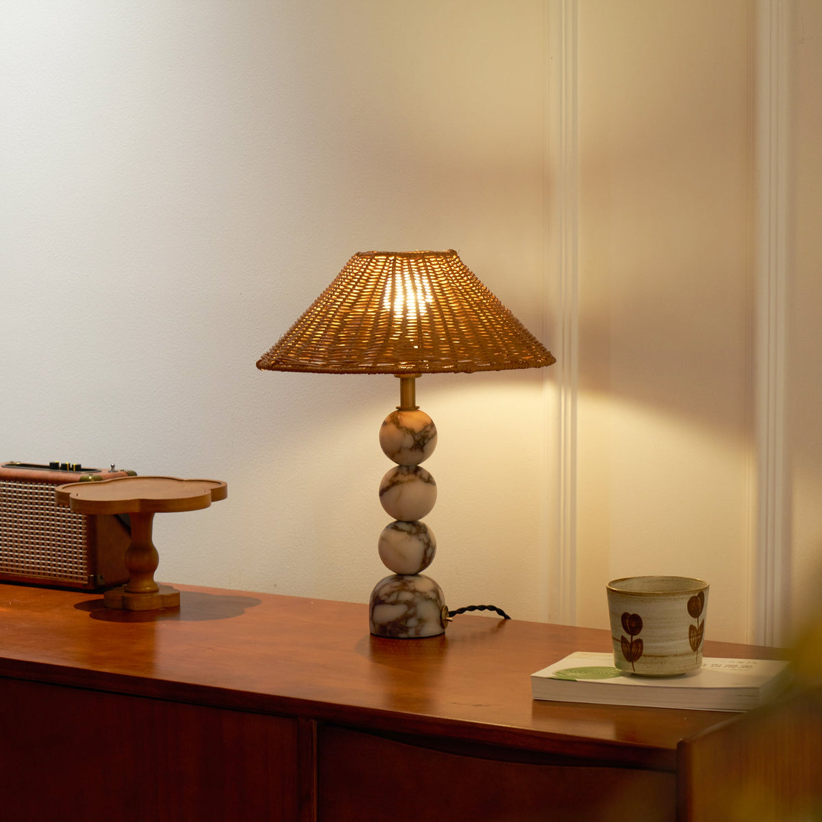 Marble-based Clérachic table lamp glowing softly on a wooden sideboard, with a small tray and a cup in the warm light.