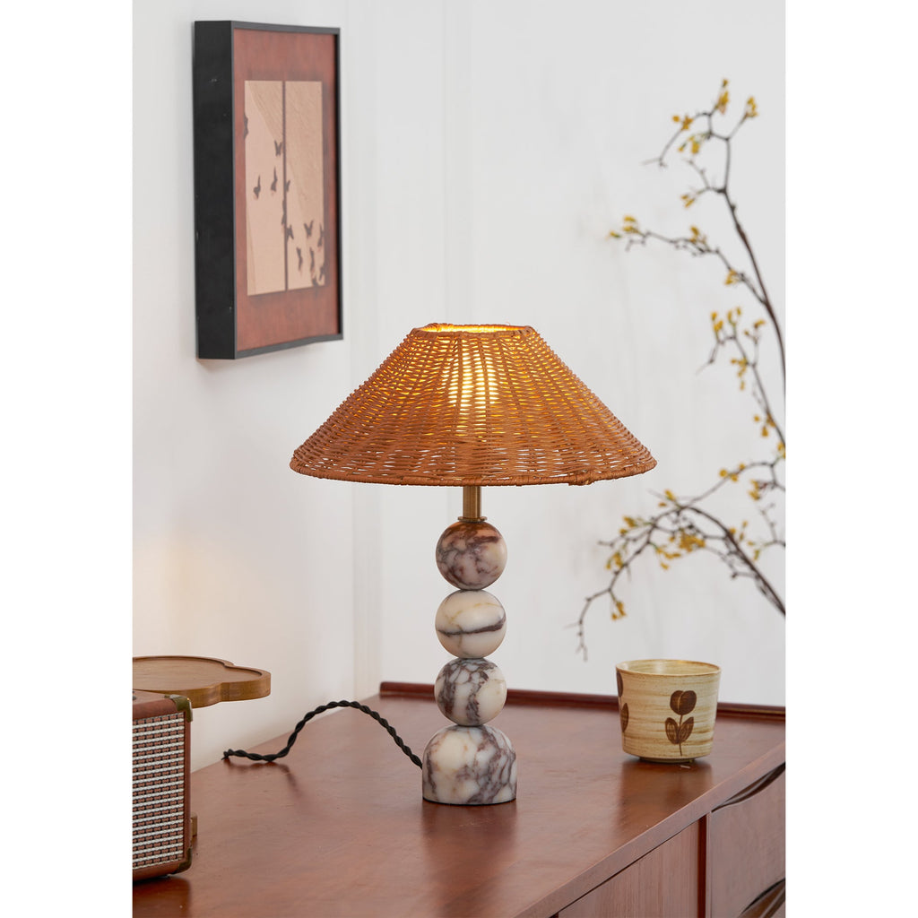 Side angle on a lit Clérachic table lamp, with a retro radio and a cup on the teak sideboard and a blossom branch behind.