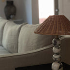 Close view of the marble spheres and rattan shade of this Clérachic lamp beside a linen sofa arm in soft daylight.