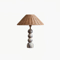 This Clérachic table lamp shown on a white background, with three marble spheres on a rounded foot under a rattan shade.