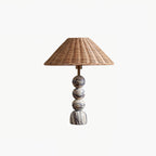 This Clérachic table lamp shown on a white background, with three marble spheres on a rounded foot under a rattan shade.