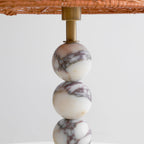 Close view of the brass stem joining the rattan shade to the veined marble spheres of this Clérachic lamp.