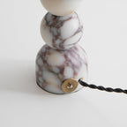 Close view of the marble foot of this Clérachic lamp, with its brass cord entry and black twisted cord.