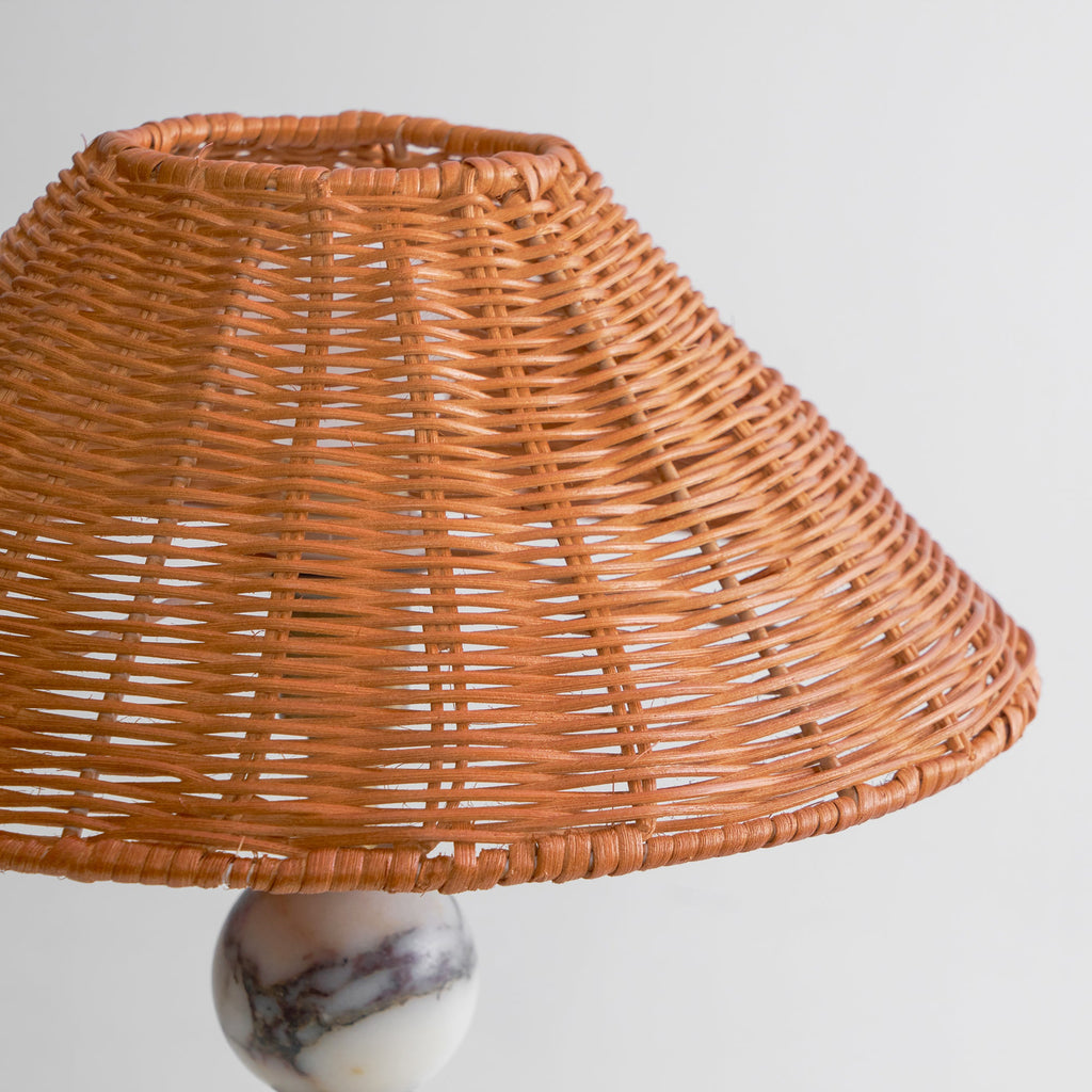 Close view of the woven rattan weave on the shade of this Clérachic table lamp, seen from slightly below.