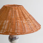 Close view of the woven rattan weave on the shade of this Clérachic table lamp, seen from slightly below.