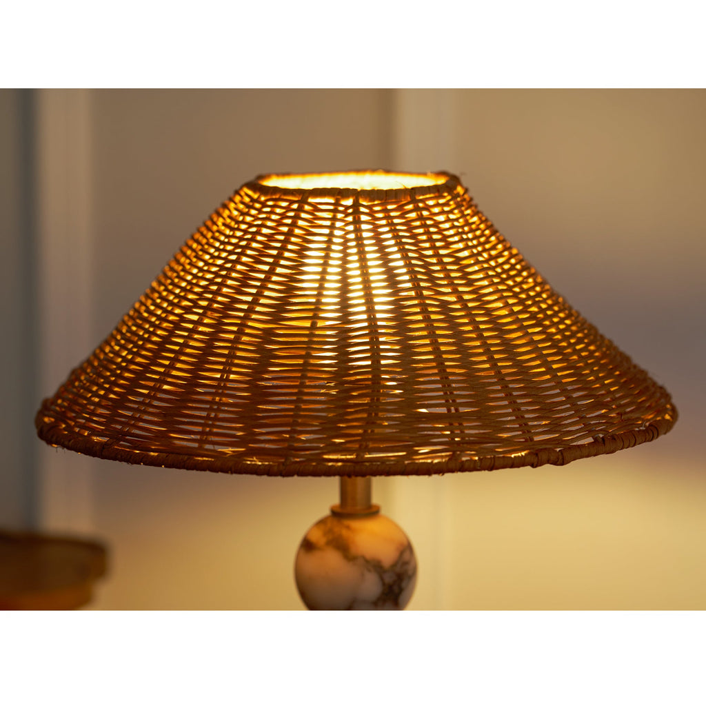 Close view of this Clérachic lamp's rattan shade glowing amber, with the light shining through the open weave.