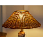 Close view of this Clérachic lamp's rattan shade glowing amber, with the light shining through the open weave.