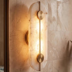 Angled close-up of the Clérachic oval alabaster sconce shows its veining and brass bar against tiled stone.