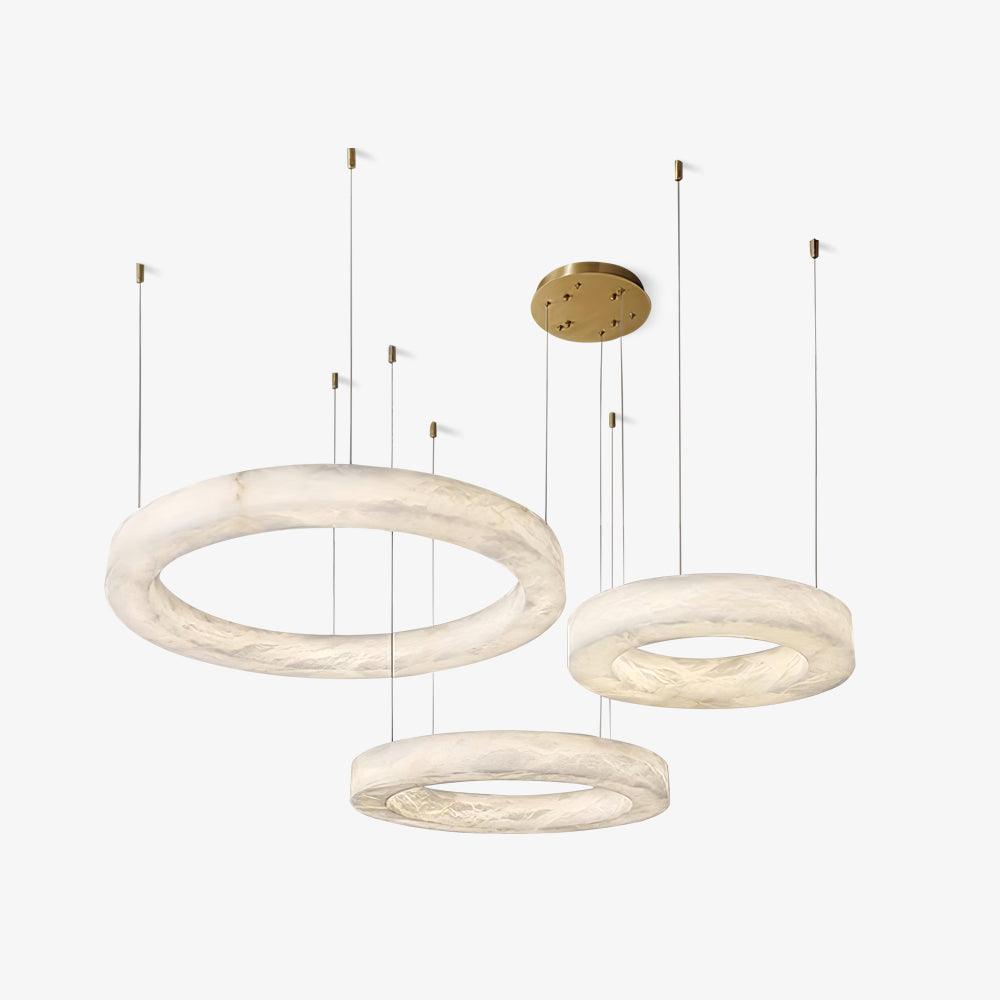 Three Clérachic Marika rings on white, staggered at different heights from one brass plate.