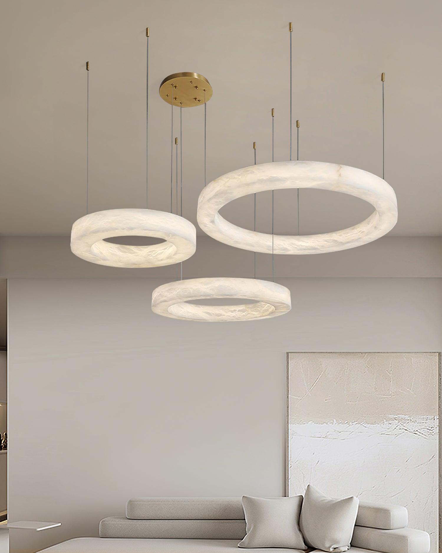 The Clérachic Marika three-ring set lit above a low sofa beside a textured canvas.