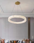 A single Clérachic Marika ring lit above a sofa, its stone band glowing against the ceiling.