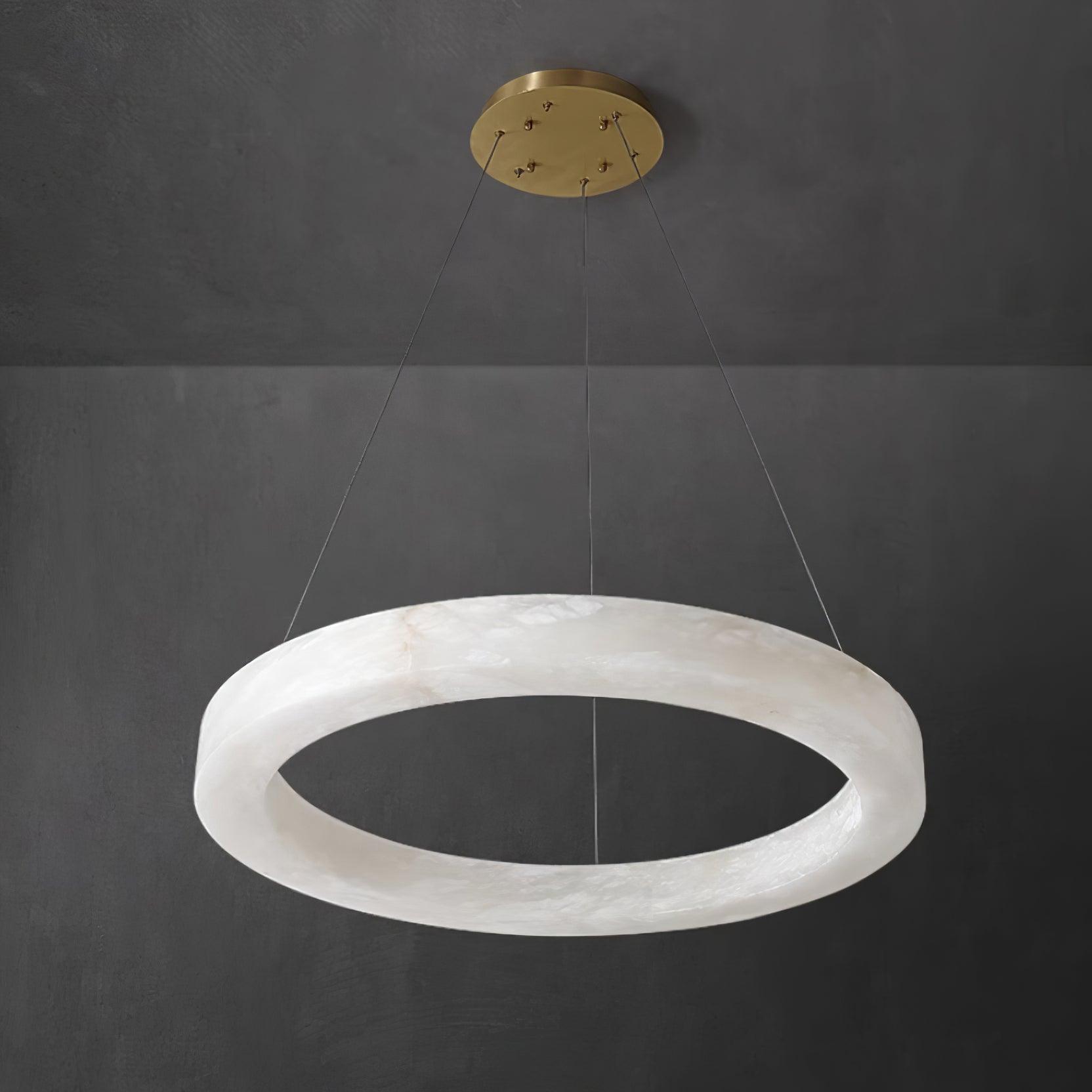 The Clérachic Marika ring on dark grey, brass canopy above the lit alabaster torus.