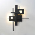 A Clérachic wall light on a pale wall, with a warm light shining through its two square cutouts and around the black panels.