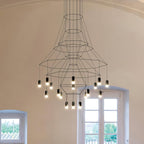 A tall Clérachic wire-frame chandelier hangs in a rounded white hall beside a French window, its LED terminals glowing in tiers.