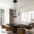 Black Clérachic wire-frame chandelier hung over a dark oval dining table with tan chairs, in a bright kitchen-diner with tall windows.