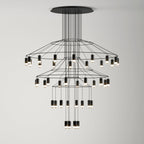Three-tier Clérachic wire chandelier with ringed frames and LED drops stepping down towards a lit cluster at the bottom.