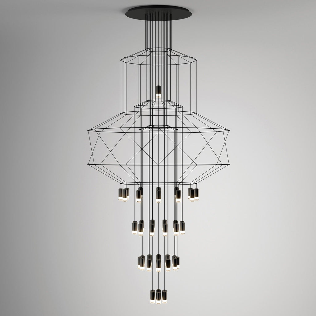 Studio view of the stacked-frame Clérachic chandelier, its octagonal wire shapes above rows of LED drops on a soft grey wall.