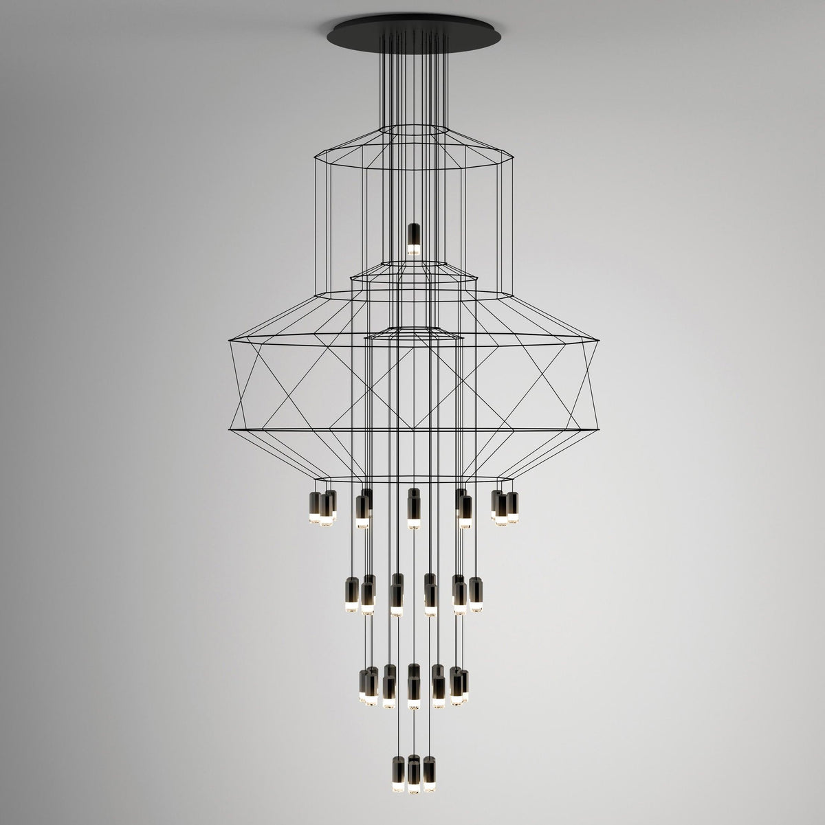Studio view of the stacked-frame Clérachic chandelier, its octagonal wire shapes above rows of LED drops on a soft grey wall.