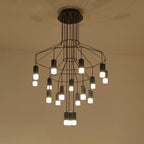 Under-view of a lit Clérachic wire chandelier with two tiers of black frames and about twenty LED drops, on a cream ceiling.