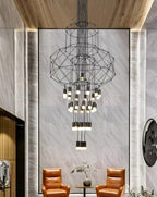 Tall stacked-frame Clérachic wire chandelier in a marble-clad lobby, with two orange leather armchairs far below.