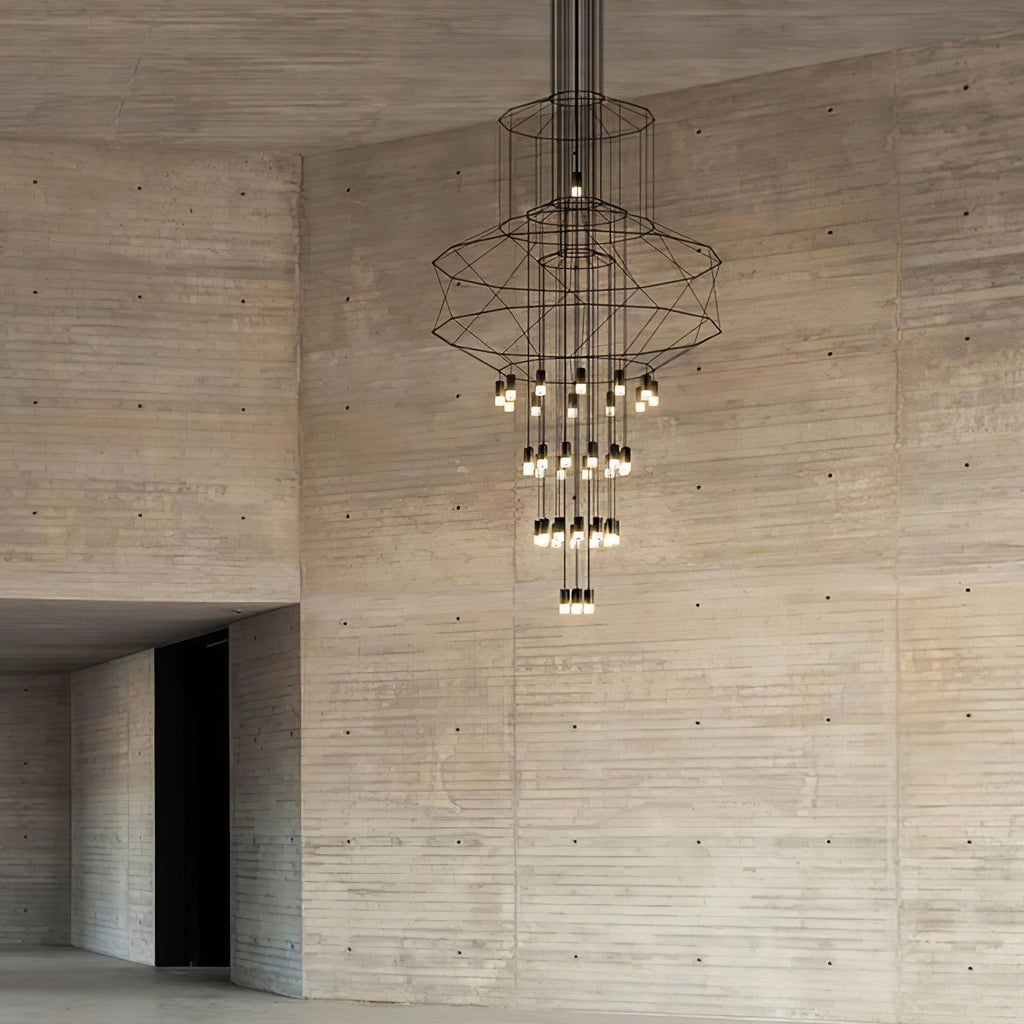 Clérachic wire chandelier with its lit LED drops, hung in front of a tall board-marked concrete wall.