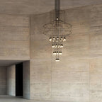 Clérachic wire chandelier with its lit LED drops, hung in front of a tall board-marked concrete wall.