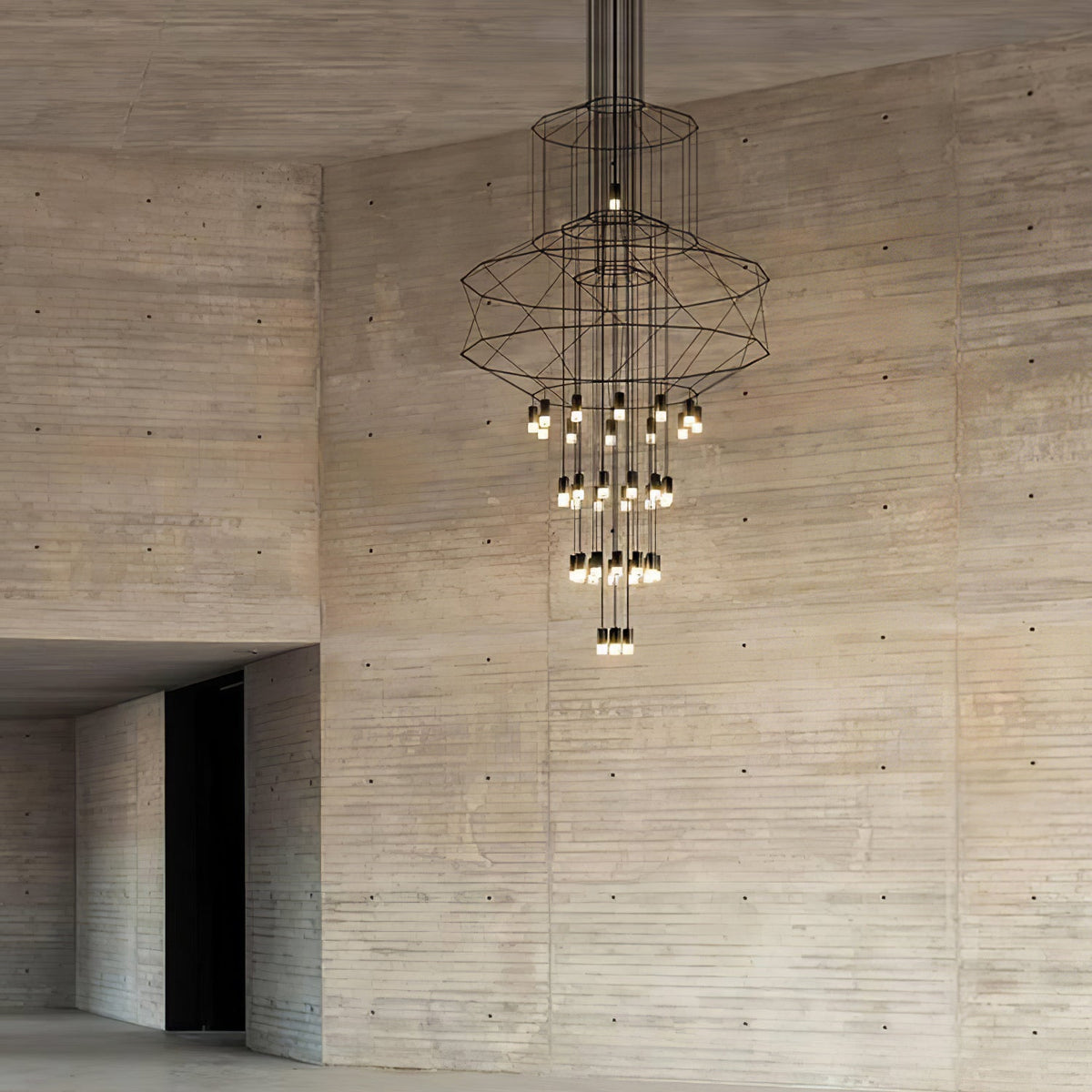 Clérachic wire chandelier with its lit LED drops, hung in front of a tall board-marked concrete wall.