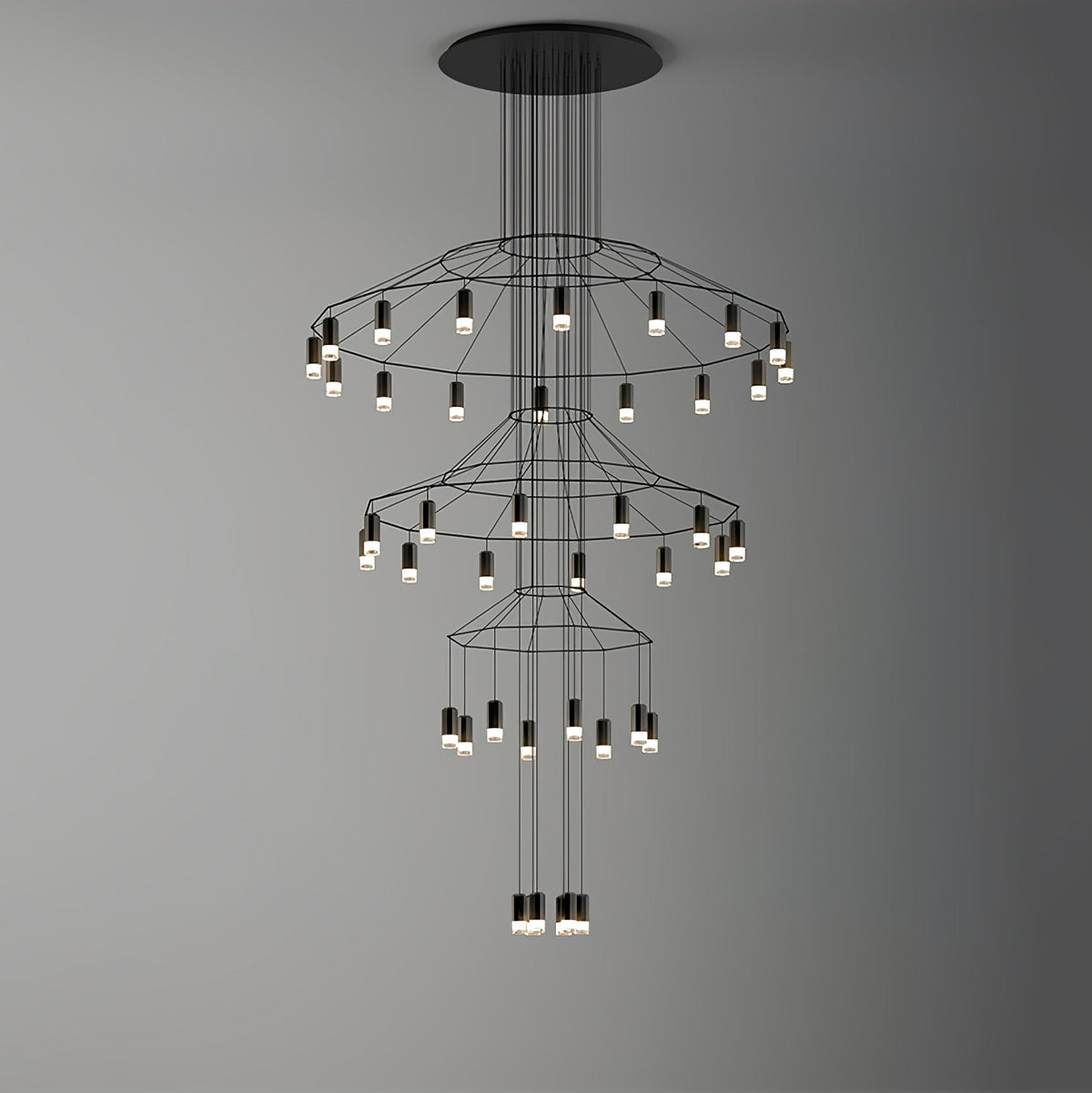 Clérachic wire chandelier with three wide tiers of LED drops hung on a grey backdrop that darkens to the right.