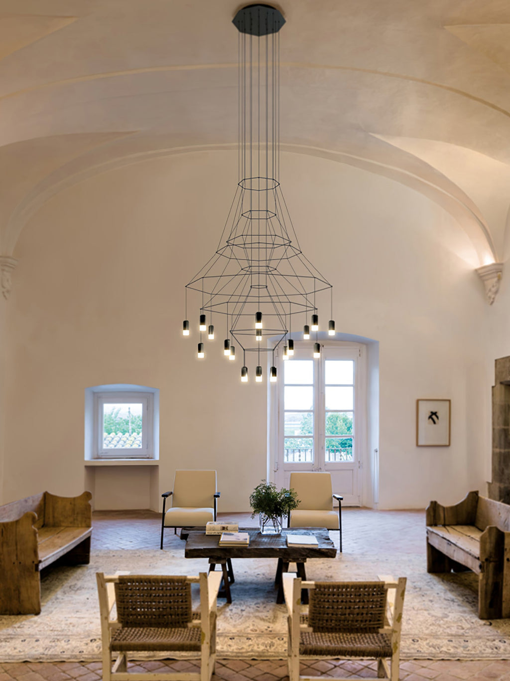 Clérachic wire chandelier with flared frames and lit LED drops hanging in a vaulted room above armchairs and benches.