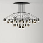 Wide, low Clérachic wire chandelier with a round canopy, thin wires and many LED drops hung at varied heights, on pale grey.