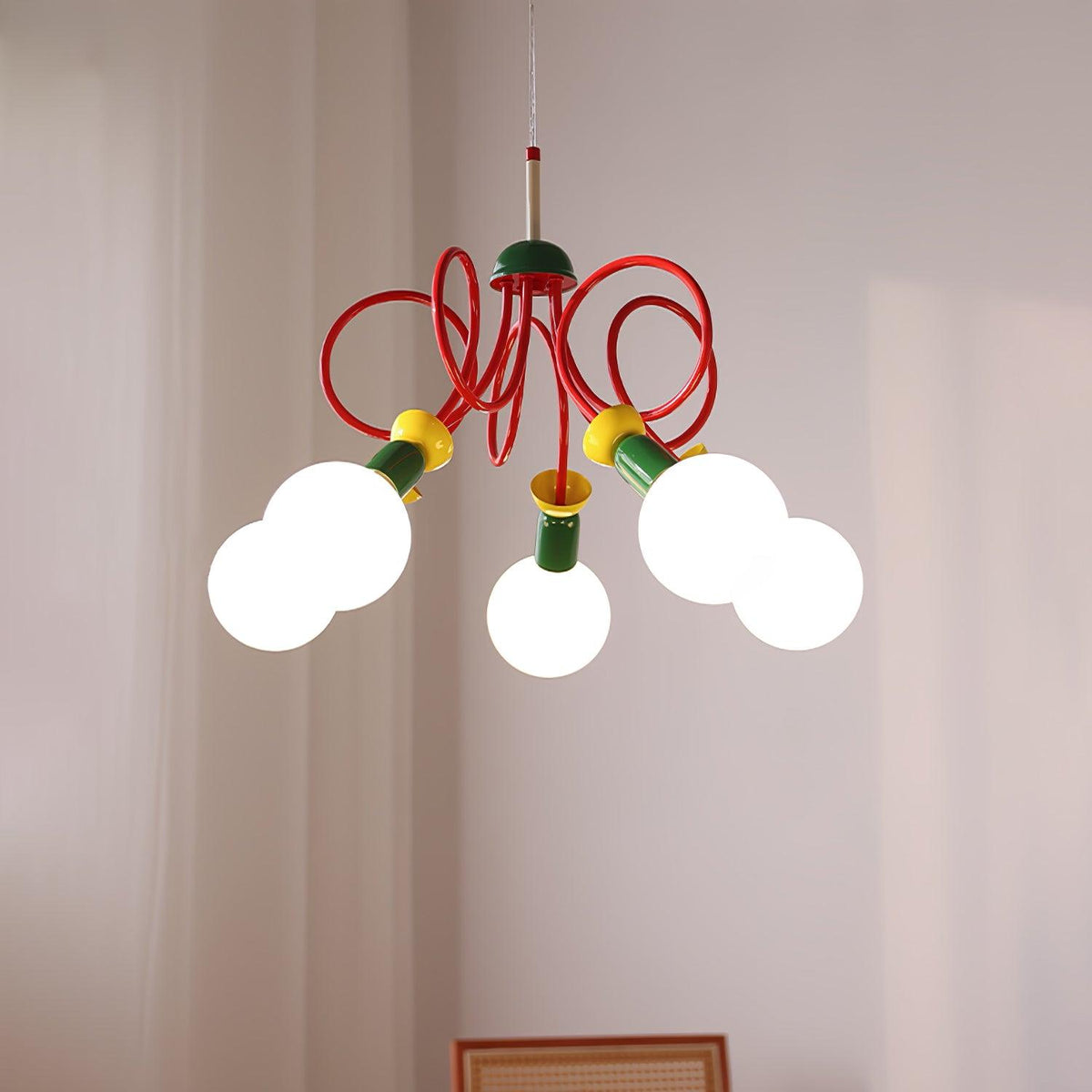 Five frosted globes under tangled red loops on this Clérachic pendant, with white curtains and a wooden frame behind.