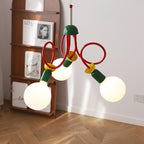 Close angle on three globe bulbs and the red looping arms of this Clérachic pendant, beside a wooden shelf and a herringbone floor.